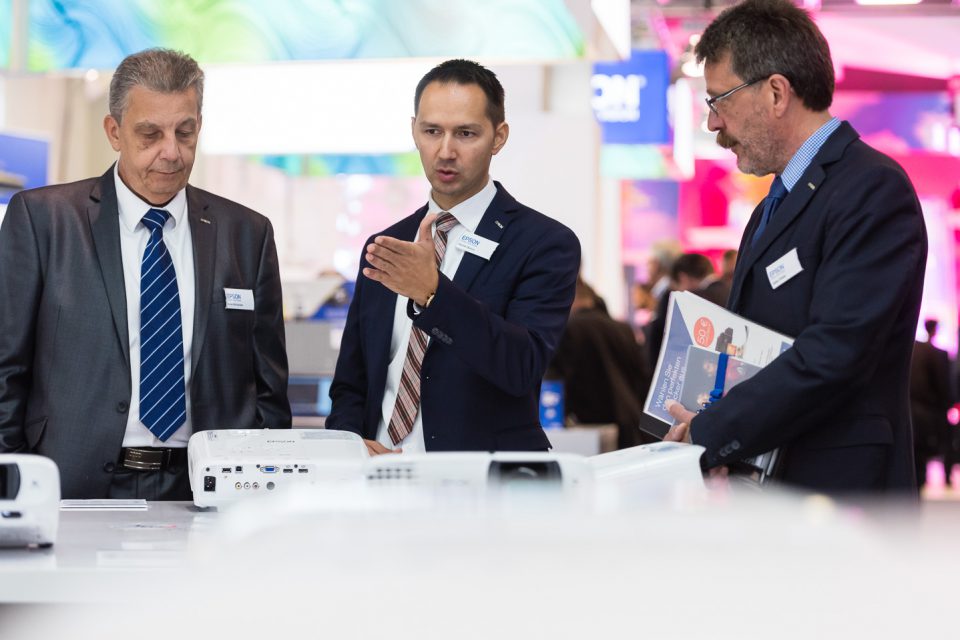 Fachbesucher diskutieren über epson beamer auf der Messe